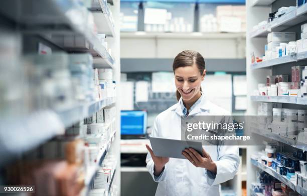 mache ein paar untersuchungen am arbeitsplatz - female pharmacist with a digital tablet stock-fotos und bilder