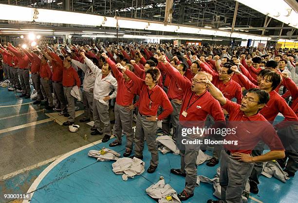 Workers cheer during the roll-out ceremony to commemorate the Fuga sedan at Nissan Motor Co.'s Tochigi plant in Tochigi Prefecture, Japan, on...