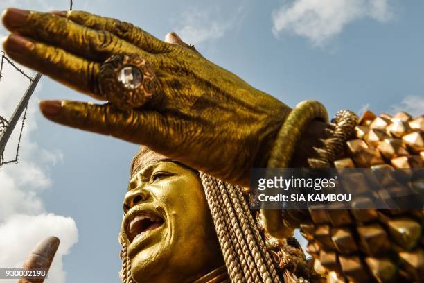 Woman painted in gold takes part in a parade during the start of MASA in Abidjan on March 10, 2018. Created in 1993 under the impetus of the...