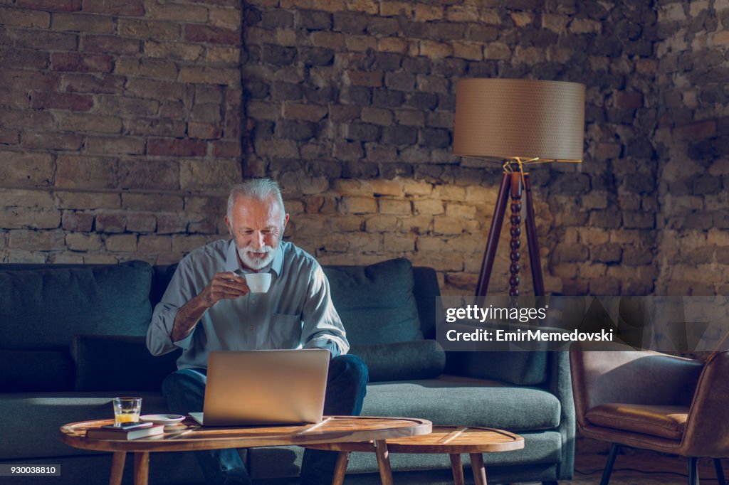 Ältere Mann mit Laptop beim Entspannen zu Hause