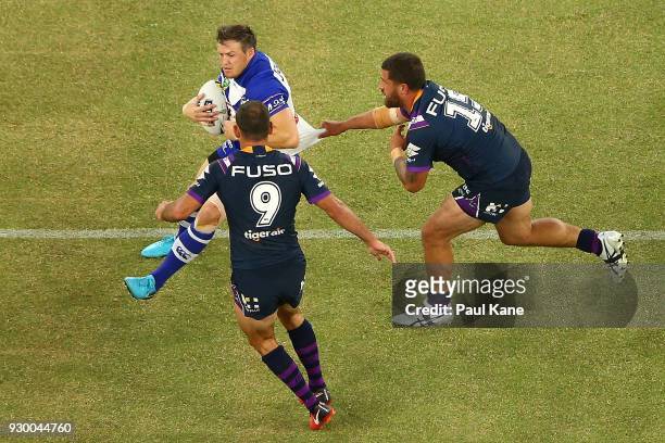 Brett Morris of the Bulldogs looks to break from a tackle by Kenneath Bromwich of the Storm during the round one NRL match between the Canterbury...