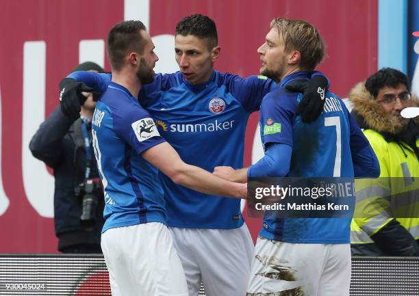 Tim Vaeyrynen of Rostock jubilates with team mate Soufian Benyamina and Pascal Breier after scoring the first goal during the 3.Liga match between FC...