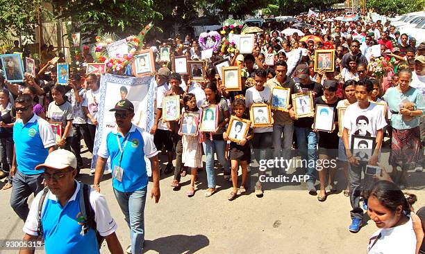 People march carrying portraits of killed relatives as they participate in a memorial for the 1991 massacre, in the Santa Cruz cemetery in Dili on...