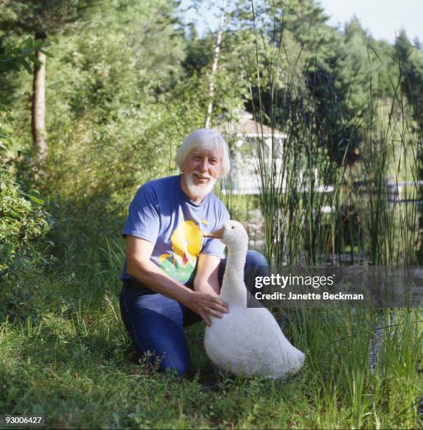 Portrait of American puppeteer Caroll Spinney, best known for his portrayal of Big Bird on 'Sesame Street,' as he poses on a water bank with a plush...