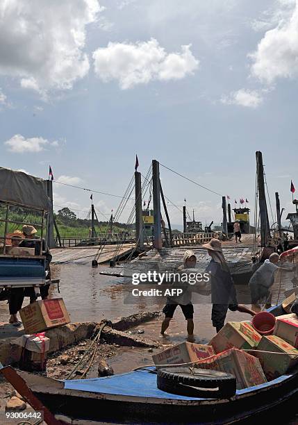 Workers unload goods from boats travelling across the Mekong river from Thailand to Laos on October, 15 2009 at the Thai-Lao border town of Huay Xay....
