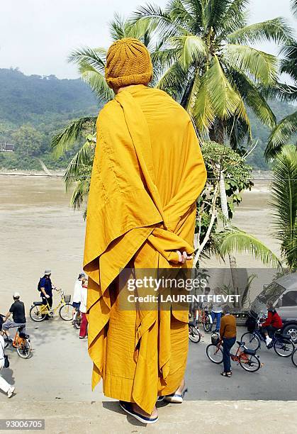 An elderly Laotian monk dressed in a saffron robe watches tourists on bicycles on the shores of the Mekong river in Luang Prabang, Laos, 03 December...