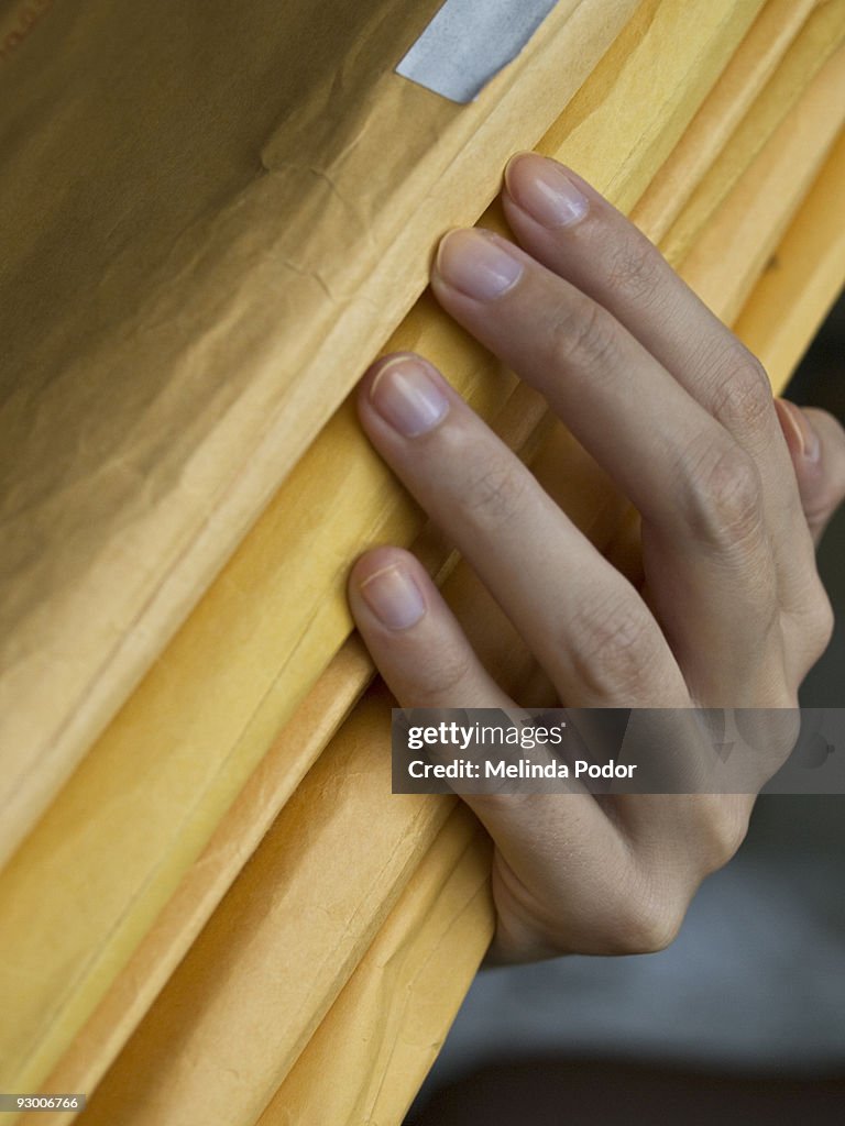 Hand holding a stack of manila envelopes