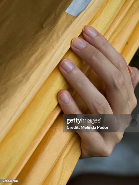 hand holding a stack of manila envelopes - brown envelope stock pictures, royalty-free photos & images