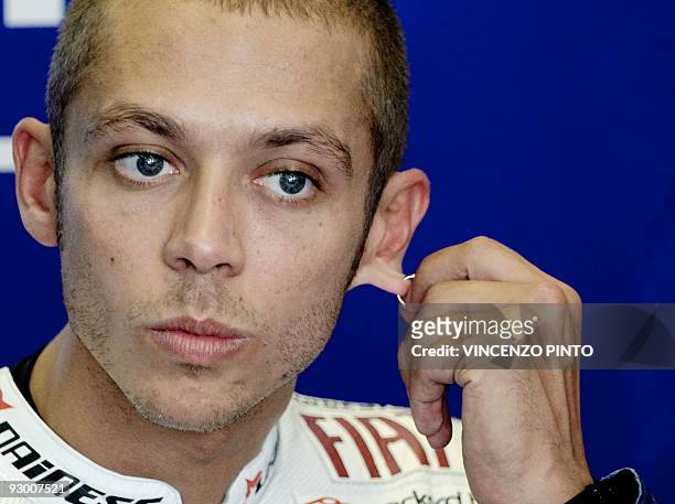 Italian moto GP Yamaha rider Valentino Rossi gestures with his ear piercing in the pits prior to the first practice session of the San Marino Grand...