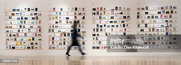Royal College of Art employee walks past a selection of postcards at the Royal College of Art Secret Postcard Exhibition on November 12, 2009 in...