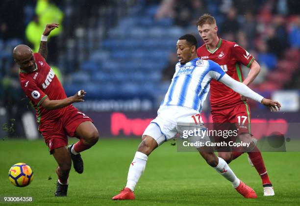 Rajiv van La Parra of Huddersfield Town is challenged by Andre Ayew of Swansea City and Samuel Clucas of Swansea City during the Premier League match...