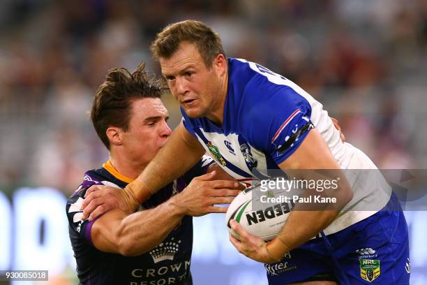 Josh Morris of the Bulldogs fends off a tackle during the round one NRL match between the Canterbury Bulldogs and the Melbourne Storm at Optus...
