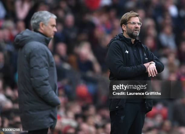 Jurgen Klopp of Liverpool looks at his watch in front of Jose Mourinho of Manchester United during the Premier League match between Manchester United...