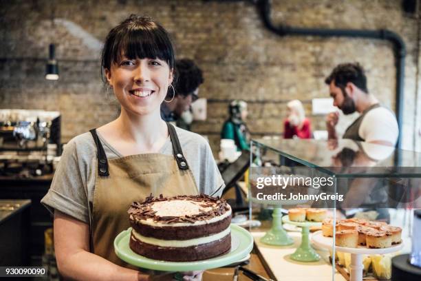 glad ung kvinna håller hembakade kakor i kaféet leende - cake bildbanksfoton och bilder