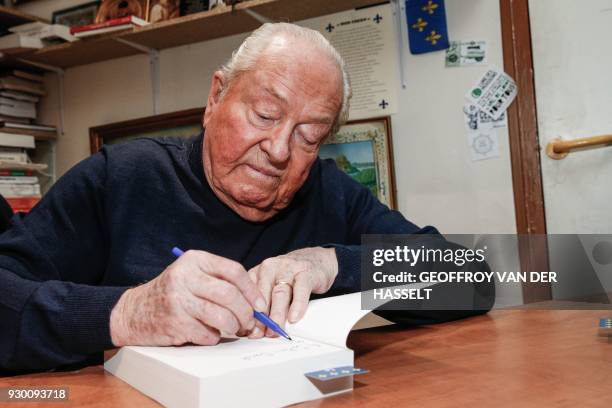 French far right party Front National honorary president Jean-Marie Le Pen autographs a copy of his Memoires' first volume "Fils de la Nation" during...