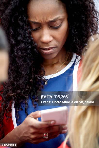 woman looking at smartphone with worried expression on face - frowning stock pictures, royalty-free photos & images
