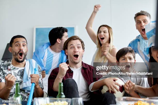 argentinian football fans cheering while watching match at home - cheering encouragement stock pictures, royalty-free photos & images