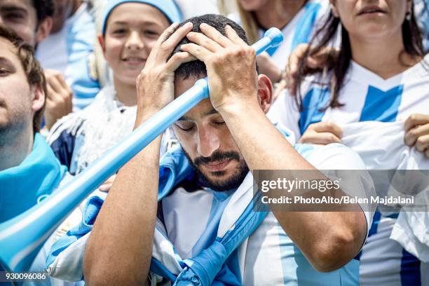 argentinian football fan holding head in disappointment at match - argentina fan fotografías e imágenes de stock