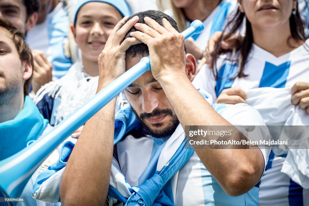 Argentinian football fan holding head in disappointment at match