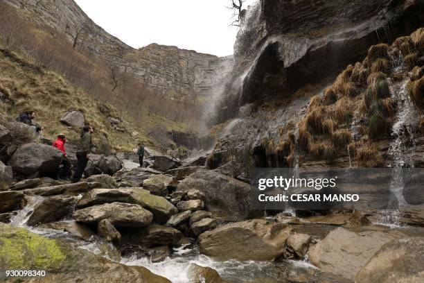 People walk through the canyon of the Salto del Nervion waterfall near Berberana in the Spanish province of Burgos on March 10, 2018. The...