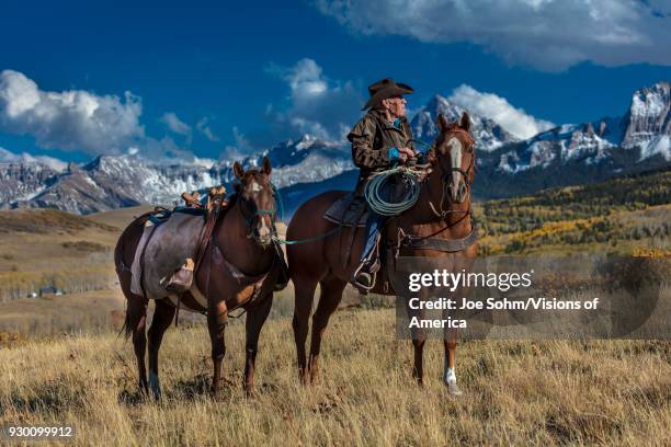 Older Cowboy, Howard Linscott , leads packhorse across historic Last Dollar Ranch on Hastings Mesa, SW Colorado, San Juan Mountains.