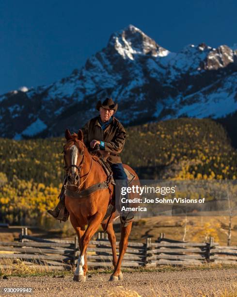 Older Cowboy, Howard Linscott , leads packhorse across historic Last Dollar Ranch on Hastings Mesa, SW Colorado, San Juan Mountains.