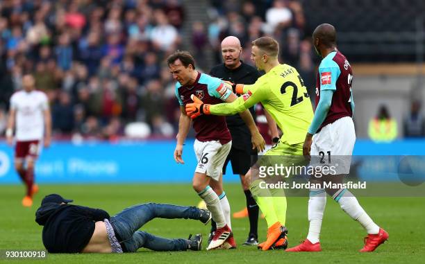 Mark Noble of West Ham United clashes with a pitch invader during the Premier League match between West Ham United and Burnley at London Stadium on...