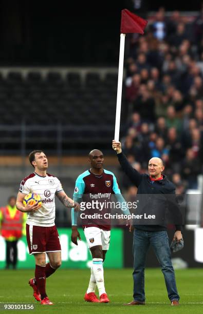 West Ham United fan holds up the corner flag while he invades the pitch as Ashley Barnes of Burnley reacts during the Premier League match between...