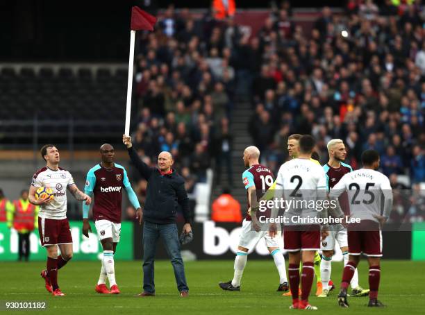 West Ham United fan holds up the corner flag while he invades the pitch as the players react during the Premier League match between West Ham United...