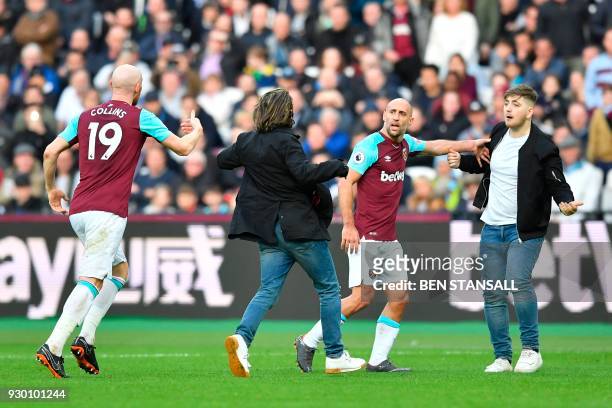 West Ham United's Argentinian defender Pablo Zabaleta and West Ham United's Welsh defender James Collins interact with pitch invaders during the...