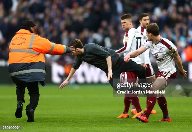 Pitch Invader is tackled by a steward, Johann Gudmundsson of Burnley and Ashley Barnes of Burnley during the Premier League match between West Ham...