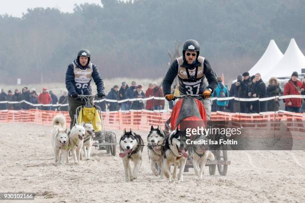 Andre Tegeler alias DJ Moguai and German actor Markus Knuefken run with sled dogs during the 'Baltic Lights' charity event on March 10, 2018 in...
