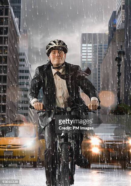 businessman biking in rain - ropa protectora deportiva fotografías e imágenes de stock