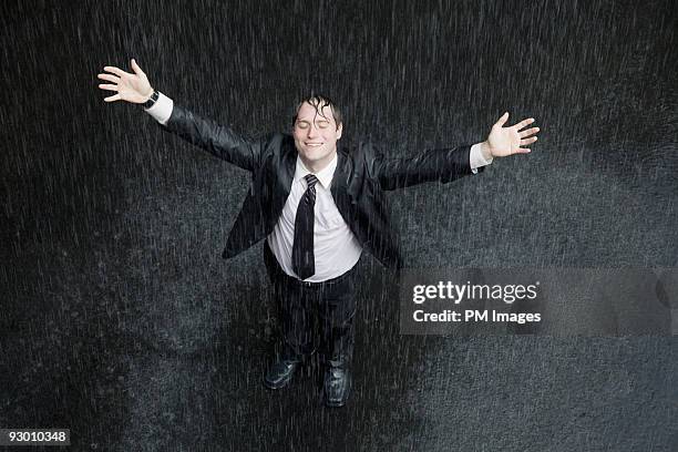 businessman smiling in rain - empapado fotografías e imágenes de stock