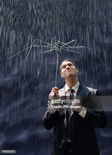 businessman with broken umbrella - broken umbrella stockfoto's en -beelden
