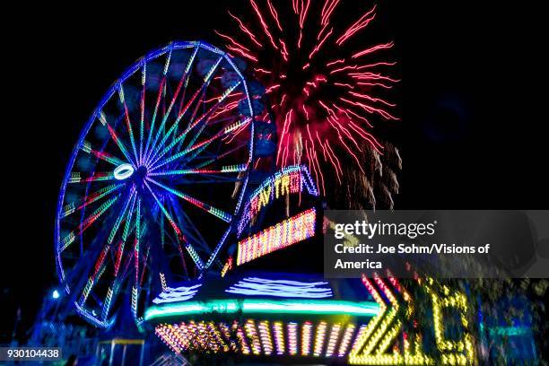 Illuminated Ferris wheel with neon lights and fireworks at the Ventura County Fair, Ventura, California.