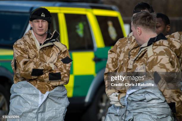 Military personnel wearing protective suits cover two ambulances with tarpaulin as they prepare to remove them from Salisbury ambulance station as...