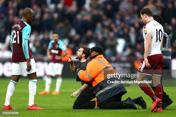 Steward tackles a pitch Invader during the Premier League match between West Ham United and Burnley at London Stadium on March 10, 2018 in London,...