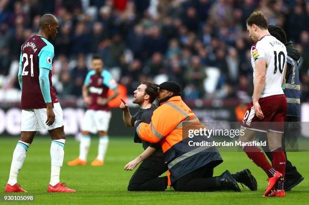 Pitch invader confronts Angelo Ogbonna of West Ham United during the Premier League match between West Ham United and Burnley at London Stadium on...