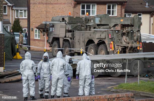 Military personnel wearing protective suits cover two ambulances with tarpaulin as they prepare to remove them from Salisbury ambulance station as...