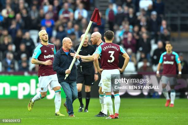 West Ham United's Welsh defender James Collins confronts a pitch invader carrying a corner flag during the English Premier League football match...