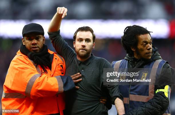 Pitch invader is escorted off the pitch during the Premier League match between West Ham United and Burnley at London Stadium on March 10, 2018 in...