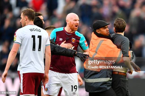 West Ham United's Welsh defender James Collins confronts a pitch invader during the English Premier League football match between West Ham United and...