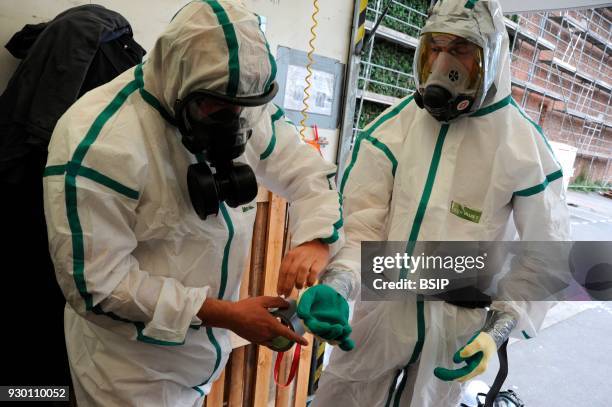 Worker Prepping for asbestos removal site, France, Regulatory clothing for each worker consists of overalls, a mask, boots and gloves. Professional...