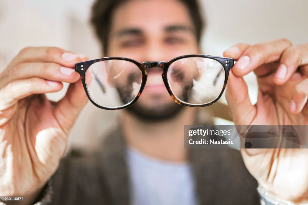 Uomo che sceglie di indossare occhiali in un negozio di ottica