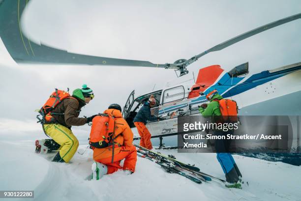 heli-skiers disembark from helicopter, on snow crest - heli skiing stock pictures, royalty-free photos & images