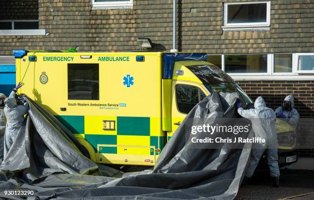 Military personnel wearing protective suits cover two ambulances with tarpaulin as they prepare to remove them from Salisbury ambulance station as...