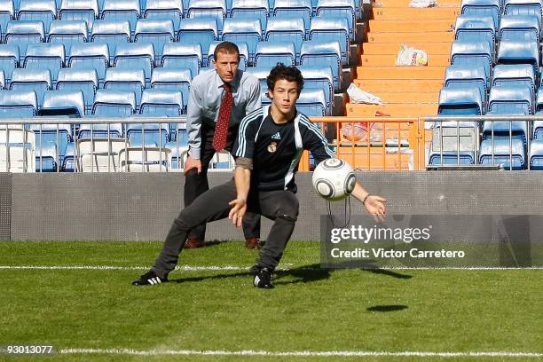 Nick Jonas of the Jonas Brothers saves a ball as Emilio Butragueno looks on during a visit as guests of Real Madrid as they visit Santiago Bernabeu...