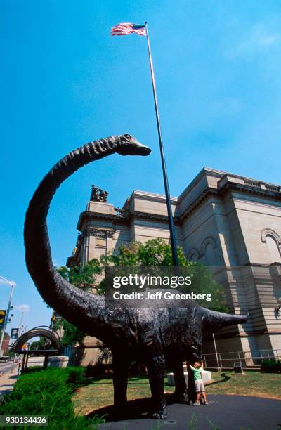 Young boy hugging a dinosaur statue outside the Museum of Natural History, Pittsburgh, Pennsylvania.