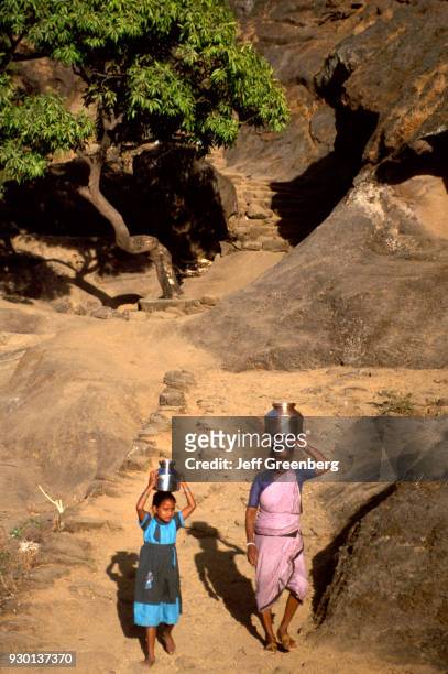Grandmother and girl carry water vessels balanced on head, Caves of Kanheri, India.